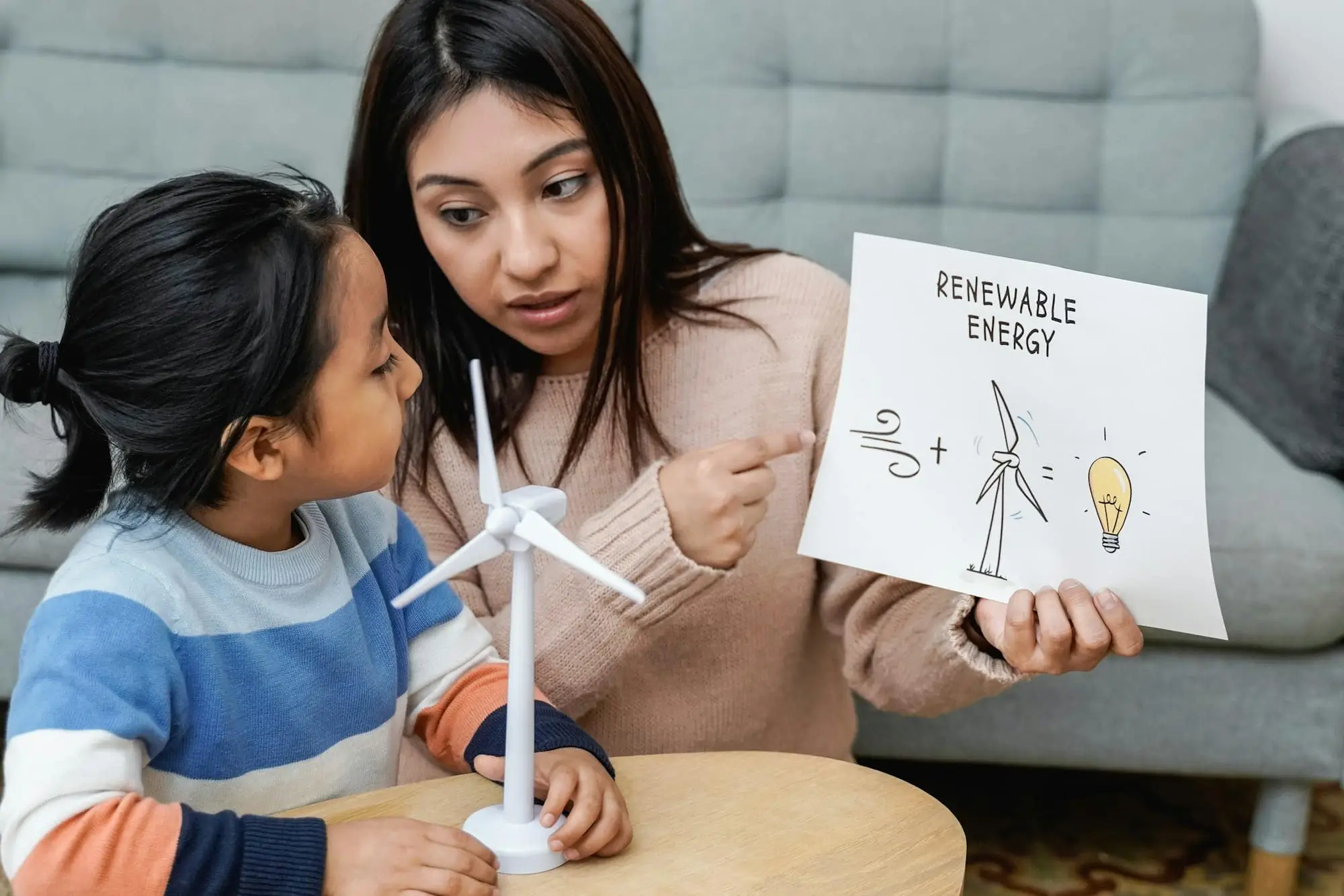 Tutor demonstrating renewable energy concepts with a miniature wind turbine to a young student during a science tutoring session in Dubai.