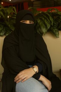 SAMEERA A FORMER IGCSE STUDENT IN DUBAI SITTING IN CAFE WITH GREEN LUSH BACKGROUND.